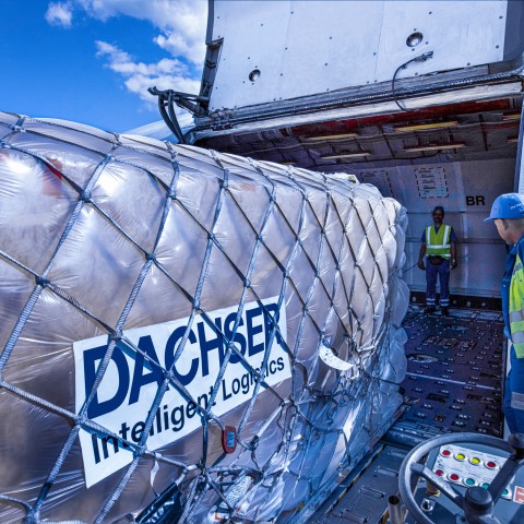 Air freight cargo secured with netting and handled by logistics personnel