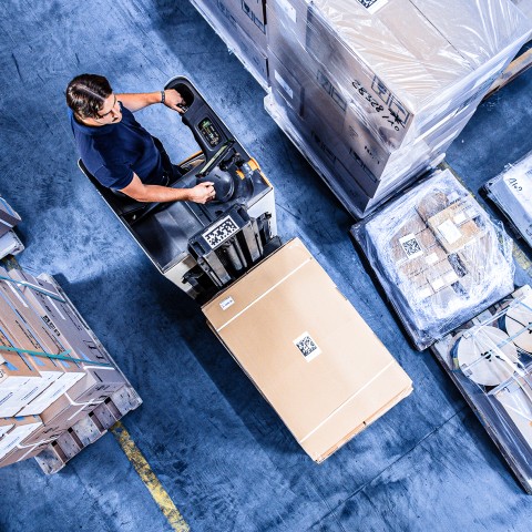 Warehouse worker handling packaged consumer goods with a forklift