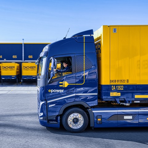 Electric DACHSER truck at a loading dock with logistics containers in the background