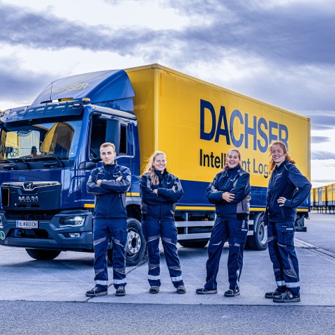 DACHSER team members standing in front of a truck and logistics trailers